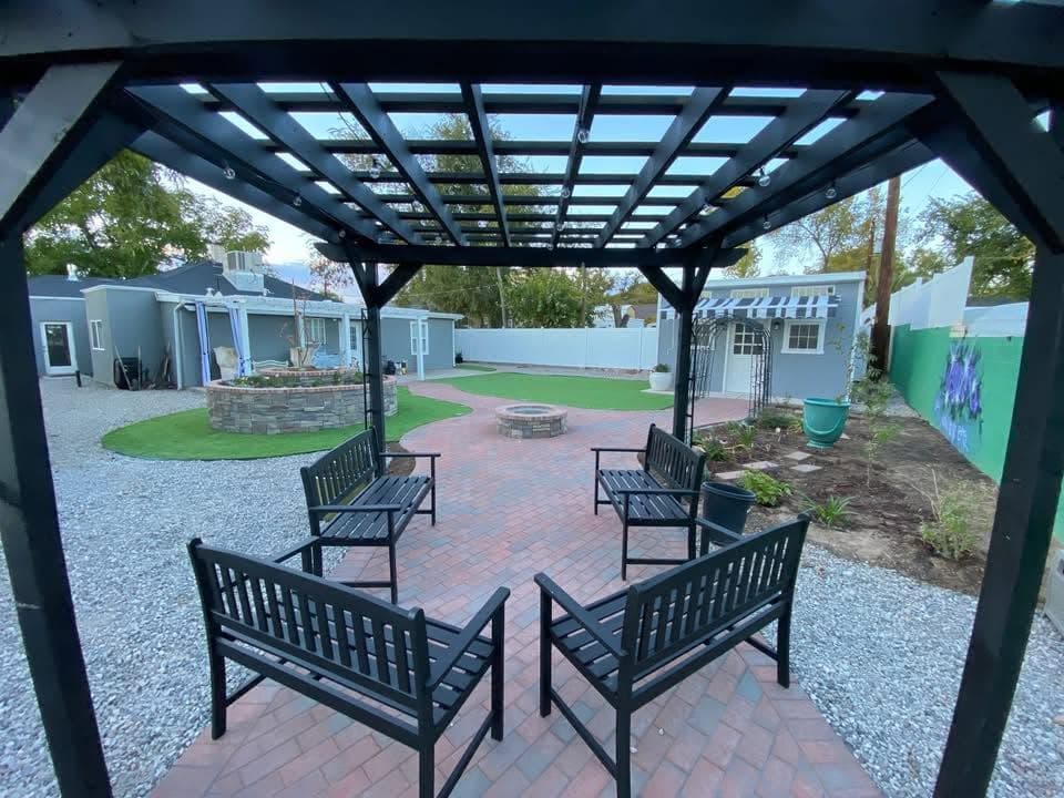 Completed outdoor living area with pergola, patio, fire pit, and masonry planters